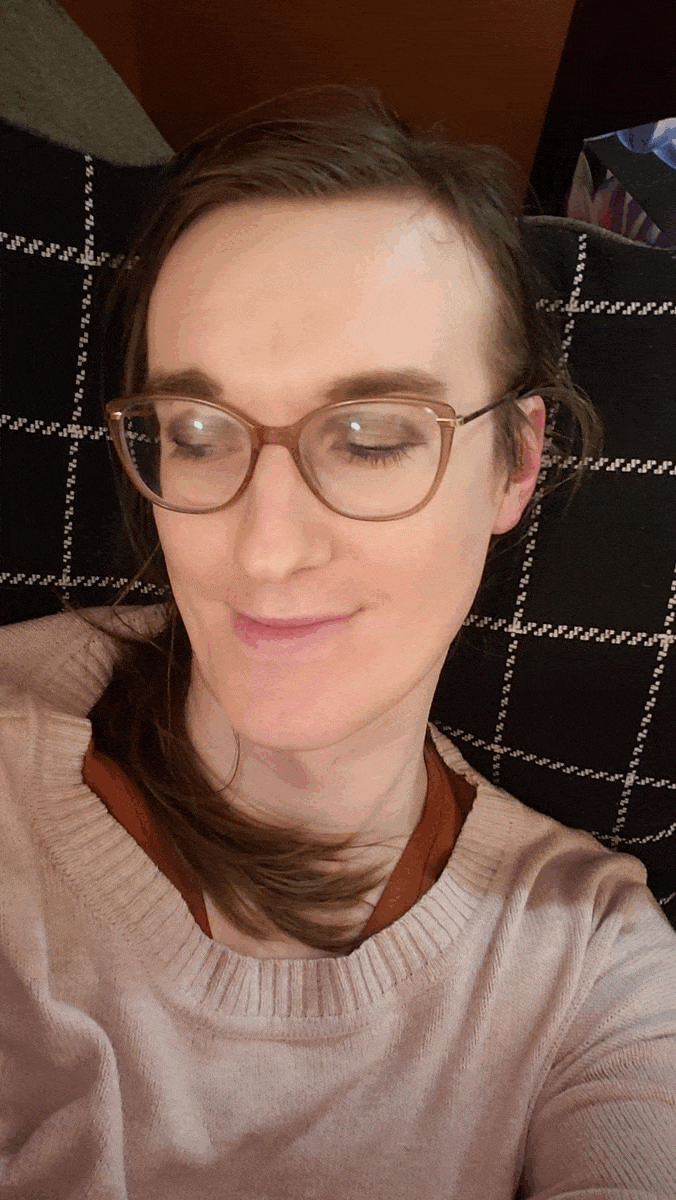 Animated GIF of me blinking at the camera in a pink sweater, hair in a loose ponytail.